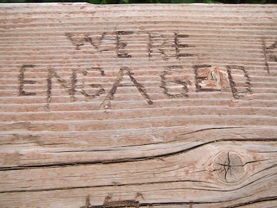 A wood plate with "we're engaged" curved in it