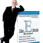 Micheal Gerber standing next to the cover of the E Myth